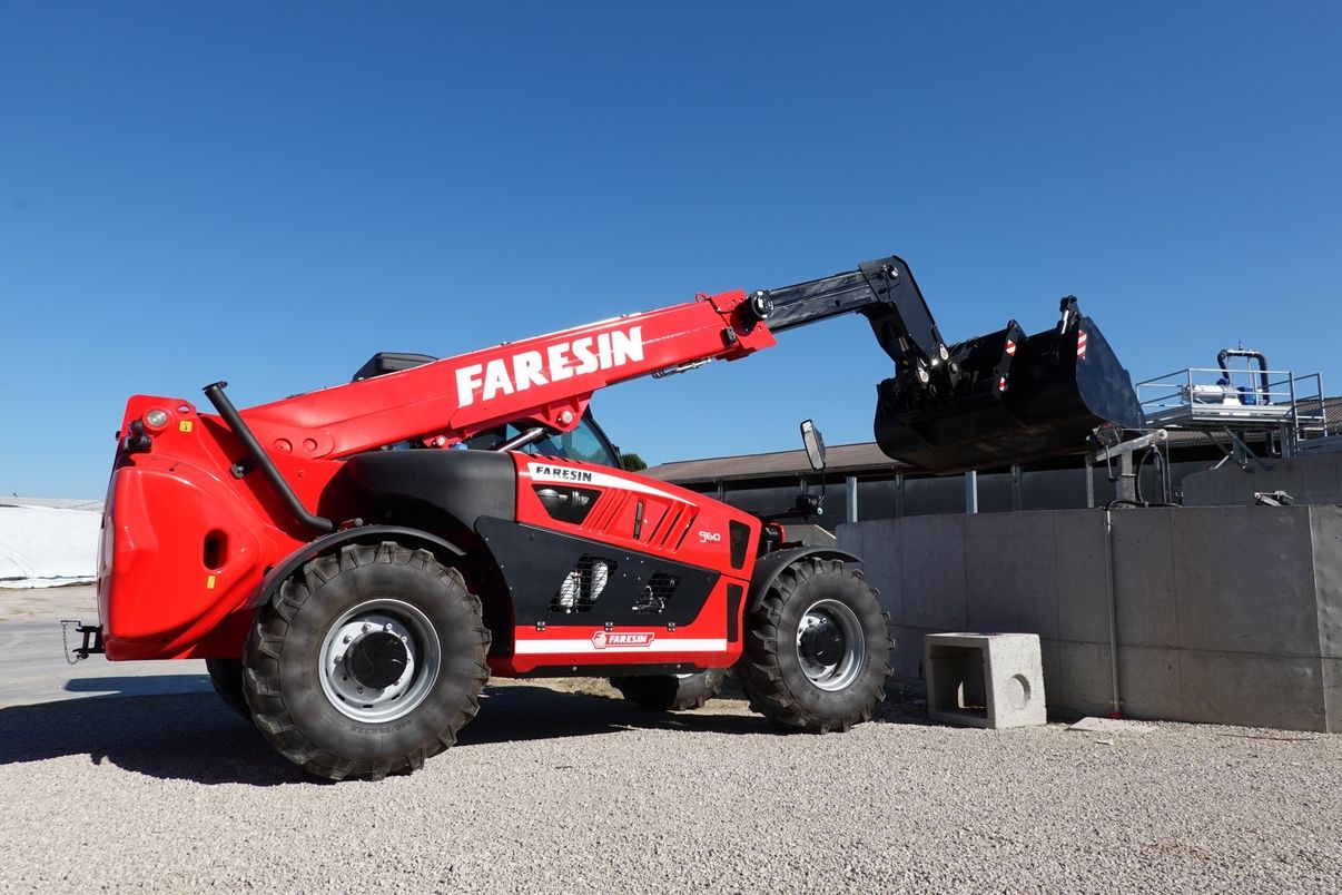 Ein roter Traktor mit Schippe von der Firma Faresin vor blauem Himmel im Hintergrund