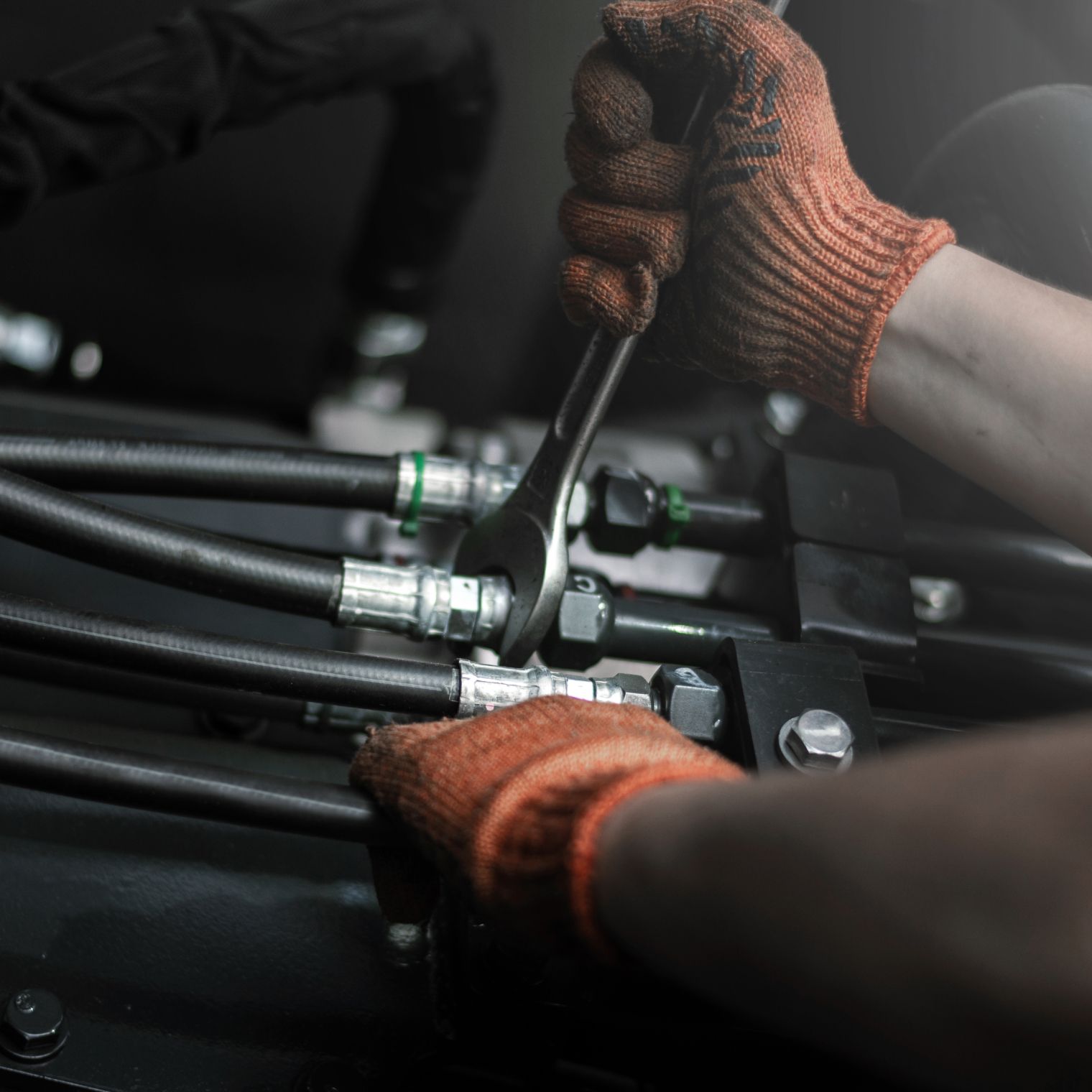 Mann mit orangen Handschuhen schraubt an Ventilen