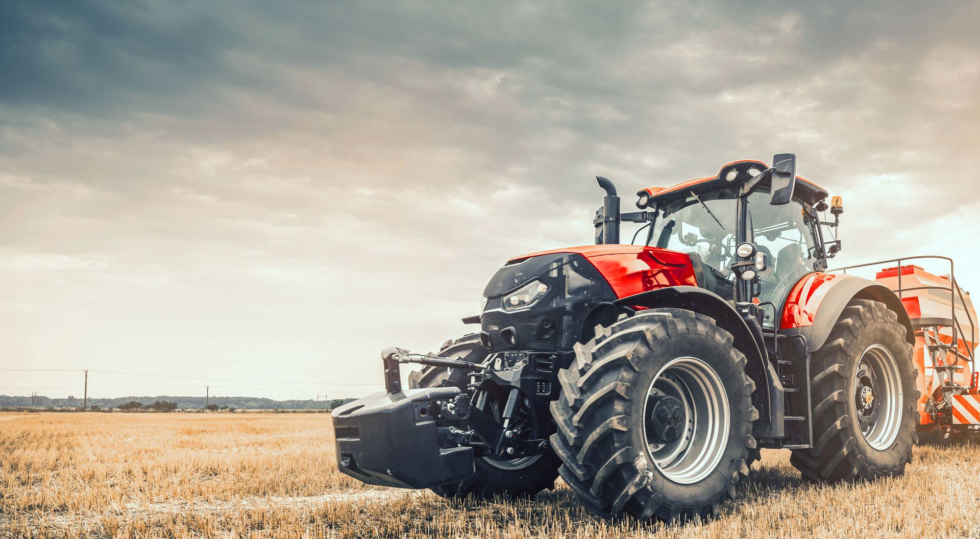 Ein roter Traktor mit Anhänger steht auf einem Feld
